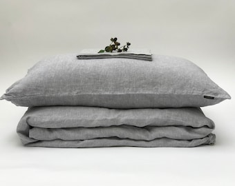 May include: A gray linen duvet cover and pillowcase set. The duvet cover is folded and the pillowcase is on top. A sprig of berries is placed on top of the pillowcase.