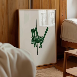 Pode incluir: Uma impressão emoldurada com uma ilustração verde de um teleférico e esquis sobre um fundo creme. A moldura é de madeira natural. A impressão é exibida em uma sala com painéis de madeira. Uma peça decorativa para a casa.