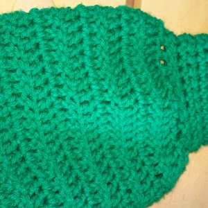 Pode incluir: Uma echarpe de croch&ecirc; verde com uma borda de renda.