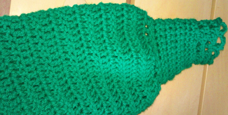 Pode incluir: Uma echarpe de croch&ecirc; verde com uma borda de renda.