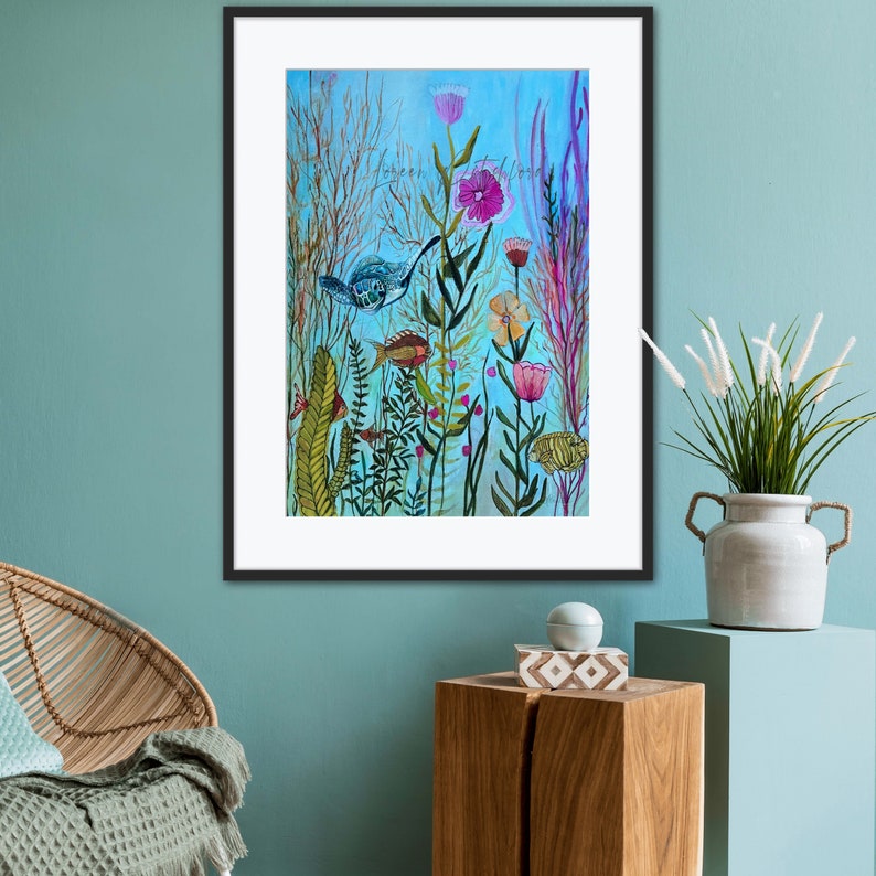 May include: A framed watercolor painting depicting an underwater scene with a blue and green turtle swimming among pink, purple, and yellow flowers, green seaweed, and orange fish. The background is a light blue color.