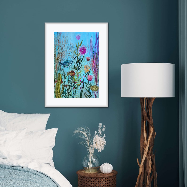 May include: A framed watercolor painting of a whimsical underwater scene with colorful flowers, plants, and a blue fish. The background is a light blue color.