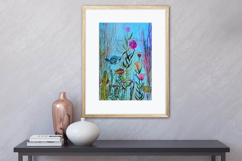 May include: A framed watercolor painting of a blue bird flying over a field of colorful flowers and green plants on a light blue background.