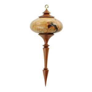 May include: A handcrafted wooden ornament with a unique design. The ornament features a light brown, bulbous center with dark accents, a dark brown stem, and a pointed tip. A small gold-colored hook is at the top for hanging. This decorative piece is ideal for holiday decor.