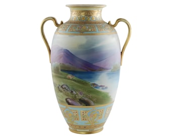 May include: A porcelain vase with gold accents and a painted landscape scene. The vase has two handles and a rounded body. The landscape scene features a lake, mountains, and trees.