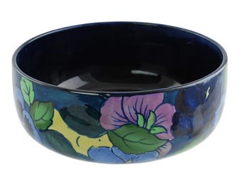 May include: A blue ceramic bowl with a floral design featuring pink, blue, yellow, and green flowers. The bowl is decorated with a floral pattern.