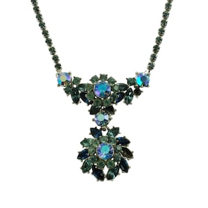 May include: A silver-toned necklace featuring a floral pendant design. The necklace has a series of small, round, teal-colored stones. The pendant is composed of various sizes and shapes of teal and blue-green stones, with a large, iridescent, round stone at the center.