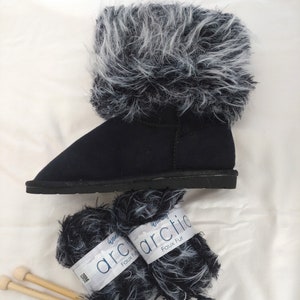 May include: Two skeins of black and white faux fur yarn with the label "Wonder Arctic Faux Fur" and two wooden knitting needles.
