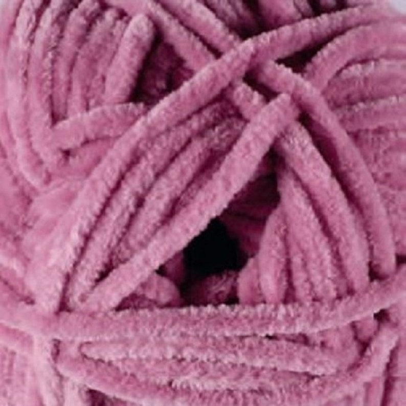 May include: A skein of soft, pink yarn with a fuzzy texture. The yarn is tightly wound and has a subtle sheen.