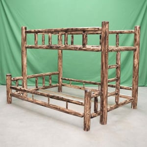 May include: A bunk bed frame constructed from dark brown and tan stained logs. The structure features a rectangular upper and lower bed frame with vertical log railings and a built-in ladder on the right side, showcasing a natural wood grain.