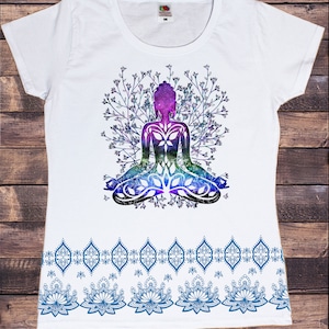 May include: White t-shirt with a colorful graphic of a meditating figure surrounded by floral branches. The bottom of the shirt features a blue and white patterned border with a repeating design of stylized flowers.