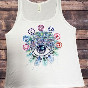May include: White tank top with a colorful eye design and seven chakra symbols. The eye is surrounded by feathers and the chakras are arranged in a circle around the eye.