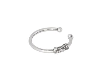 May include: A silver bangle bracelet with a decorative design on the side.