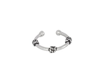 May include: Silver nose ring with three decorative knots.