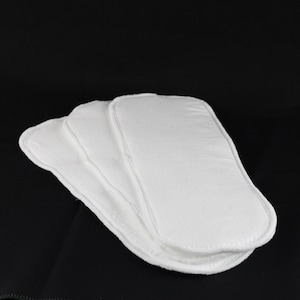 May include: Four white cloth nappy inserts. The inserts are made of a soft, absorbent material and are designed to be used with a cloth nappy cover.