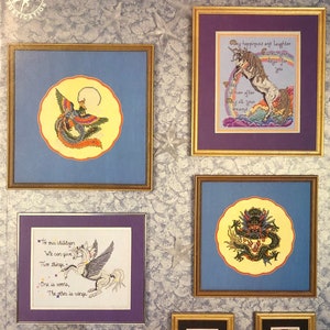 May include: A collection of five cross-stitch patterns featuring mythical creatures. The patterns include a phoenix, a unicorn, a dragon, and two pegasi. The title of the collection is "Figments of Fantasy".