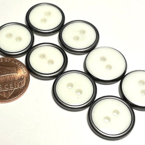 May include: Eight white buttons with a silver rim. The buttons have two holes each. The buttons are about the size of a US penny.