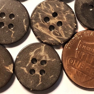 May include: A collection of brown coconut shell buttons with four holes each. The buttons are arranged in a semi-circle around a US penny.