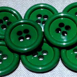 May include: A group of ten green plastic buttons with four holes each. The buttons are arranged in a semi-circle.