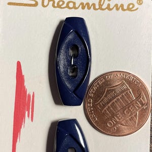 May include: Two navy blue oval-shaped buttons with a unique design, displayed on a white card with the word "Streamline" in gold lettering. A penny is next to the buttons for size comparison.
