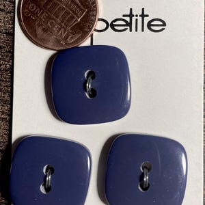May include: Three navy blue, square-shaped buttons with metal shanks are displayed on a white card. A penny is placed on the card. The card reads "petite" and "Washable". The buttons are 7/8 inches in size.