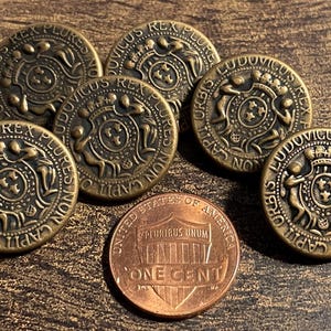 May include: A collection of seven antique bronze-colored buttons with intricate embossed designs and text. The buttons are round and feature a central emblem with surrounding text. A US one-cent coin is included for size comparison.