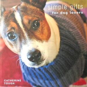 May include: A book cover featuring a close-up of a dog wearing a blue sweater. The title of the book is "simple gifts for dog lovers" and the author is "Catherine Tough".
