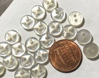 Könnte beinhalten: Eine Sammlung von 18 weißen Plastikknöpfen mit einem vierzackigen Sternmuster. Die Knöpfe sind etwa so groß wie ein deutscher Cent.