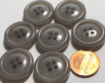 May include: Six gray plastic buttons with four holes each. The buttons are round and have a shiny finish. A penny is included for size reference.