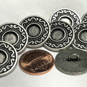 May include: A set of eight silver-toned buttons with a decorative design. The buttons have a raised, circular design with a smaller, recessed center. The buttons are approximately 1 inch in diameter.