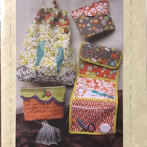 May include: Image of a sewing pattern featuring various quilted fabric bags. The bags include a drawstring bag with bird appliqués, a zippered pouch, and a roll-up bag. The pattern is titled "ON THE ROAD AGAIN - PART II".