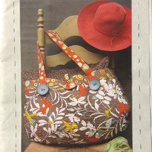 May include: A brown and tan quilted travel bag with floral and bird print fabric. The bag has two large pockets on the front and two blue buttons. The bag is 22 inches by 17 inches. "ON THE ROAD AGAIN - PART I" #RR137