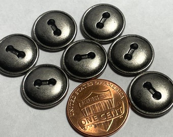 May include: Seven silver-toned buttons with a two-hole design. The buttons are approximately the size of a US penny.