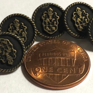 May include: Seven antique gold-toned buttons with a black background and a gold crest design. One button is shown from the back, revealing a shank.