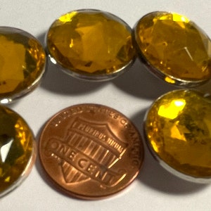 May include: Six yellow glass buttons with silver settings. The buttons are round and have a faceted design.