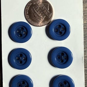 May include: A set of six round, dark blue, four-hole buttons arranged in two columns on a white card labeled Classic at the top and 59c at the bottom. A United States one-cent coin is positioned between the top two buttons for size reference.