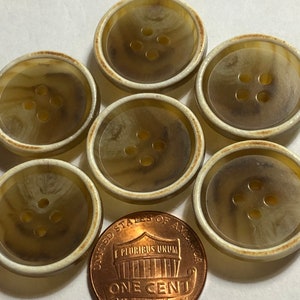 May include: Six brown and white plastic buttons with four holes each. The buttons are approximately the size of a US penny.