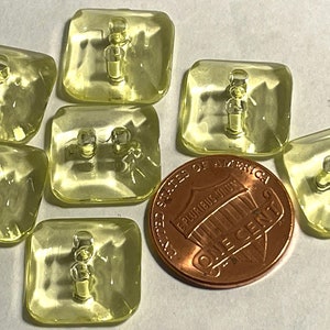 May include: Six translucent yellow square buttons with two holes each. The buttons are about the size of a US penny.