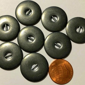 May include: Eight silver-toned metal buttons with a hole in the center and a slit for a shank. The buttons are approximately the size of a US penny.