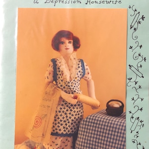 May include: A vintage-style doll dressed in a blue and white floral dress and apron, holding a rolling pin. The doll is standing in front of a blue and white checkered tablecloth. The image is titled "By Hull by Hand, Thirties Thelma, a Depression Housewife."