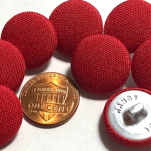 May include: Seven red fabric buttons with a textured surface. The buttons are approximately the size of a US penny.