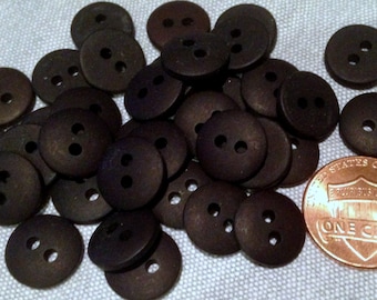 May include: A pile of dark brown wooden buttons with two holes each. The buttons are about the size of a US penny.