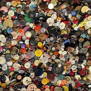 May include: A collection of various buttons in a wide array of colors, shapes, and sizes. The buttons include shades of red, yellow, blue, black, white, and brown. Some buttons have two holes, while others have four. There are also buttons with decorative designs.