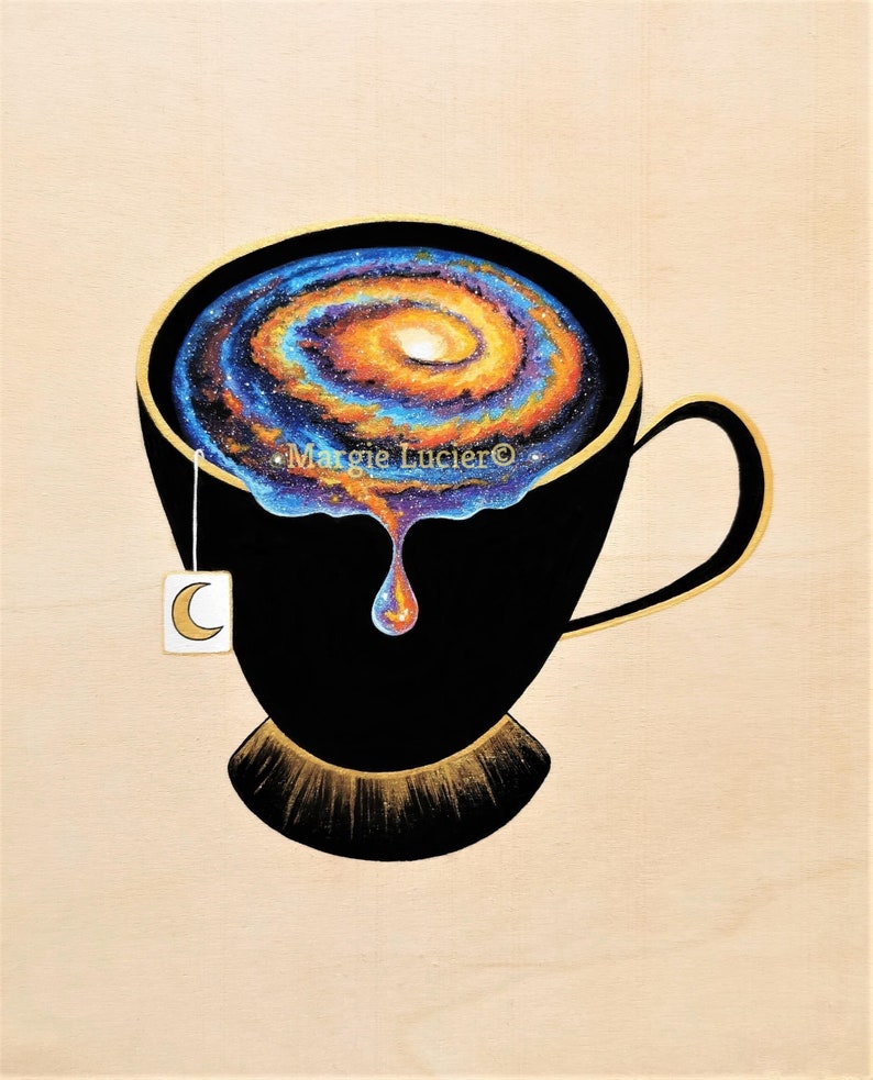Op de afbeelding: Een zwarte theekop met een gouden rand en handvat, gevuld met een draaiende, galaxie-achtige patroon in tinten blauw, oranje en geel. Een enkele druppel van de galaxie-achtige vloeistof druppelt uit de kop. Een wit theezakje met een halve maan ontwerp hangt aan de zijkant van de kop. De tekst "Margie Lucier&copy;" is zichtbaar op de kop.