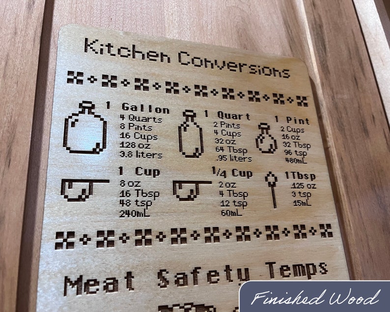 May include: Wooden kitchen conversion chart with engraved text and pixelated illustrations. Includes measurements for gallons, quarts, pints, cups, tablespoons, and teaspoons. The text "Kitchen Conversions" is at the top.