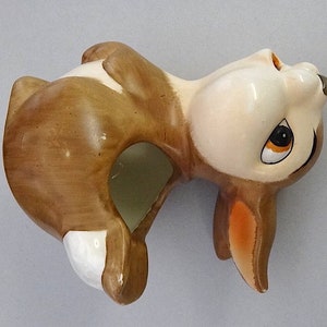 May include: A brown and white ceramic rabbit figurine with a hole in the back for planting. The rabbit is looking up with its ears perked up.