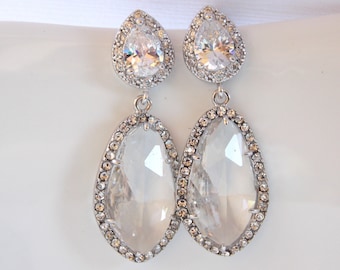 May include: A pair of silver teardrop earrings with large clear crystal stones surrounded by smaller clear crystals.