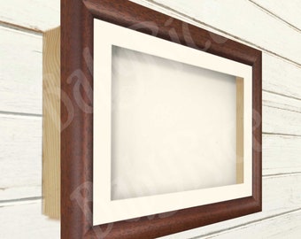 May include: A rectangular picture frame with a dark brown wooden frame and a white mat. The frame is mounted on a light-colored wooden surface. The frame is empty, ready for a photo or artwork.