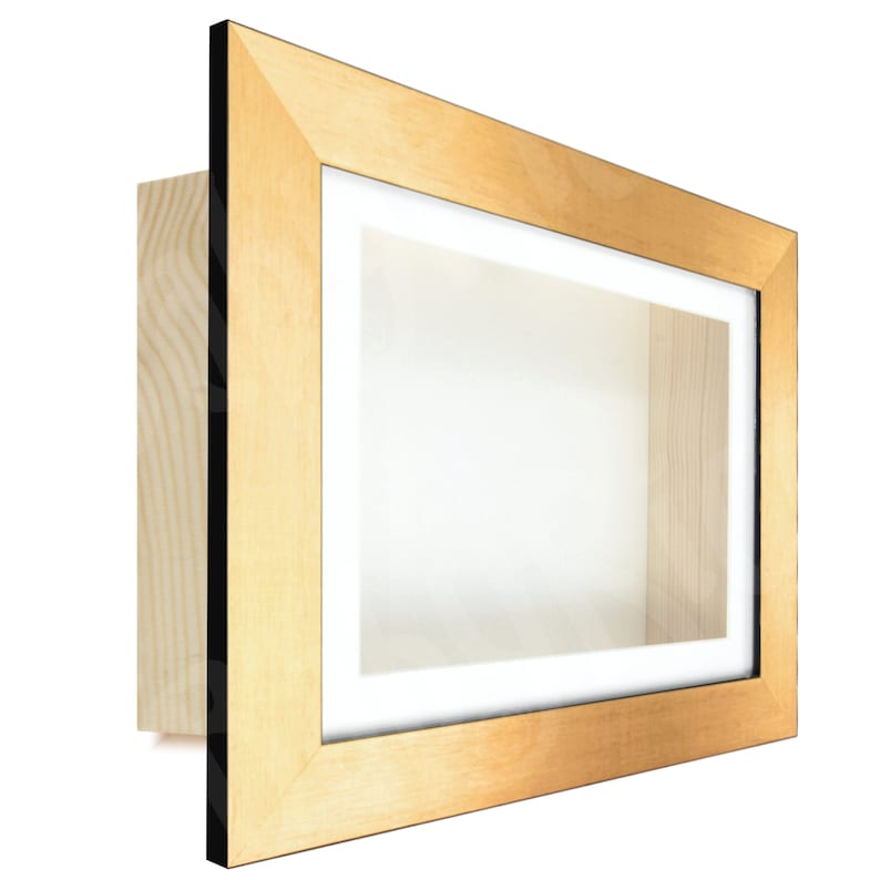 May include: A gold-colored shadow box frame with a black mat. The frame is made of wood and has a simple, modern design.