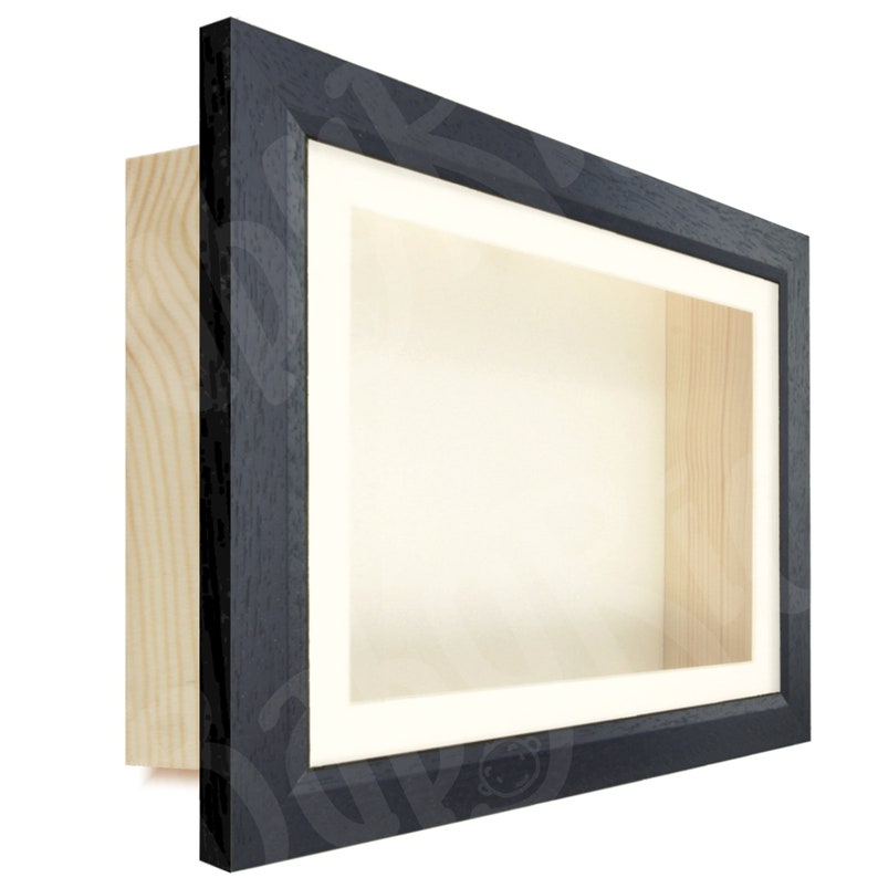 May include: Black shadow box frame with a white mat and a wood backing. The frame is made of wood and has a simple design.